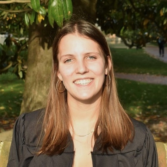 Brooke Tobias, Junior Environmental Scientist, stands outside wearing business casual attire in front of a magnolia tree.