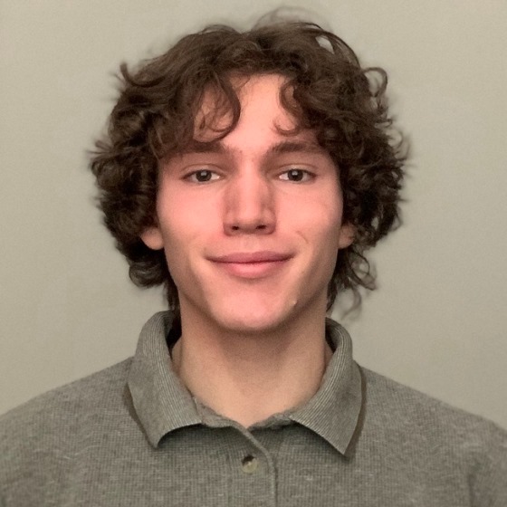 Kiefer Fallin, Junior Environmental Scientist, stands in front of a light-colored wall in business attire.